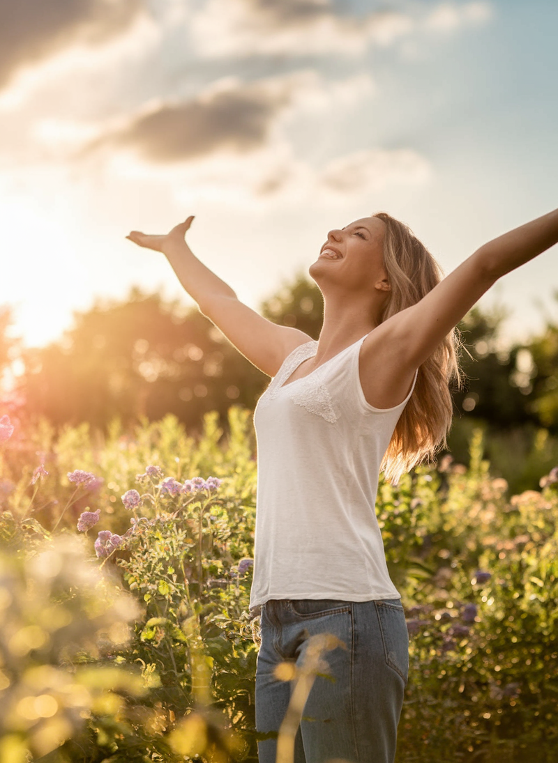 A woman cheering in a field, representing personal empowerment and finding a life you love.